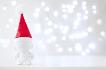 Fototapeta premium Christmas cute toy in Red Hat Santa Claus, Symbol New Year, Defocused Lights White Background