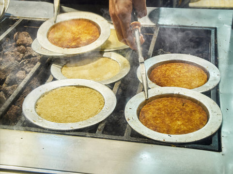 Cooking Kunefe, also known as Kenafeh, a traditional Arab dessert made with Kadayif, a thin pastry noodle, over a charcoal grill of a street stall in Istanbul.