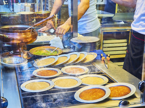 Cooking Kunefe, also known as Kenafeh, a traditional Arab dessert made with Kadayif, a thin pastry noodle, over a charcoal grill of a street stall in Istanbul.