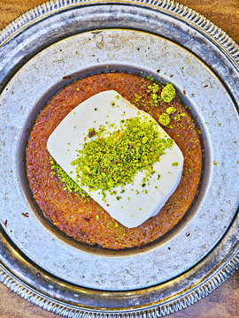 Kunefe, also known as Kenafeh, a traditional Arab dessert made with Kadayif, a thin pastry noodle, soaked in sweet syrup, layered with ice cream and topped with crushed pistachio nuts.