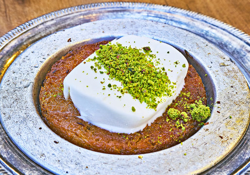 Kunefe, also known as Kenafeh, a traditional Arab dessert made with Kadayif, a thin pastry noodle, soaked in sweet syrup, layered with ice cream and topped with crushed pistachio nuts.