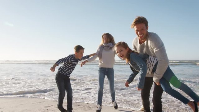 Family On Winter Beach Running Away From Advancing Waves