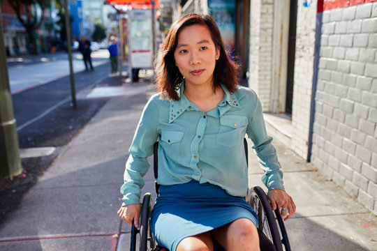 Young woman in wheelchair on sidewalk