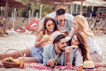 Group of happy young people having a picnic on the beach.