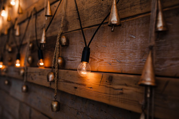 Garland lamps over wooden board fence. Decoration background.Vintage light bulb on wooden wall