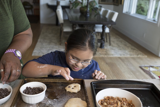 Woman teaching girl to make cookies