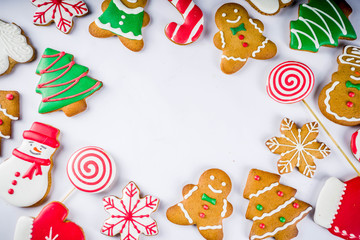 Various traditional colorful sugar glazed christmas gingerbread cookies, on white background top view copy space banner with xmas decorations