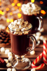 Cappuccino with marshmallow in glasses and candy cane on wooden table