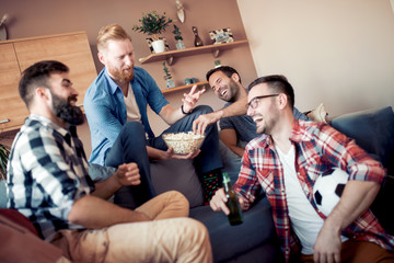 Happy male friends drinking beer at home