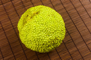 Green fruit of maclura pomifera, osage orange, horse apple, adam apple grow on bamboo mat