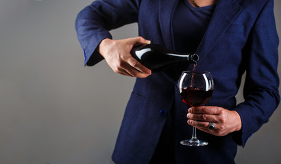 Gourmet drink bottle, red wine glass, sommelier, tasting. Waiter pouring red wine in a glass. Sommelier man, degustation, winery, male winemaker. Red wine is poured from bottle to glass.