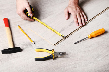 Man installing timber laminate flooring with tools