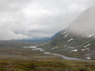 river flowing through bottom of valley among mountains in northern sweden