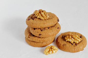 Walnuts and delicious sweet crunchy shortbread with raisins and dark chocolate. Light concrete background.