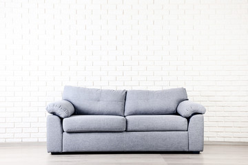 Modern grey sofa on brick wall background