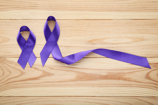 Purple ribbons on wooden table. Cancer concept