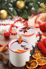Mulled wine in mugs with spices on wooden table