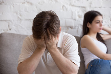 Young man and woman sitting on couch not talk, not looking of each other after quarrel at home....