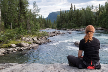 woman contemplating the rapids at Kvikkjokk in northern sweden