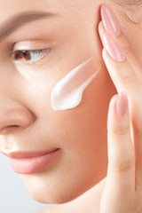 Young beautiful woman applies cream on clean perfect skin