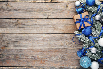 Christmas fir-tree branches with baubles and gift box on wooden table
