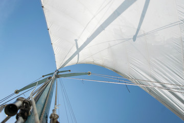 White sail of a sailing boat against sky. Sails of river sailing yacht in the wind against the blue...