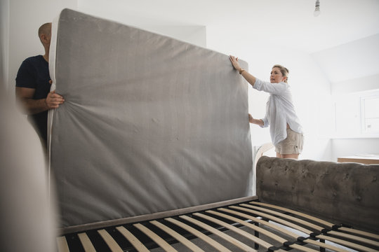 Couple Setting Up Bed Together In New Home