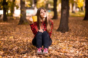Young woman drink hot tea in autumn park