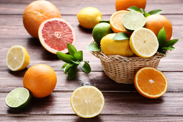 Citrus fruits with green leafs in basket on brown wooden table