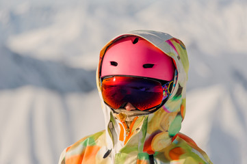 Portrait of female snowboarder in pink sports helmet and bright colorful sportswear