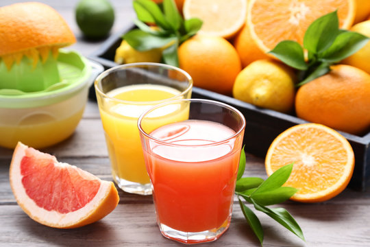 Citrus juice in glasses with fruits on wooden table