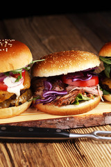 Tasty fresh meat burgers with salad and cheese. Homemade angus burger and Pulled pork sandwiches.