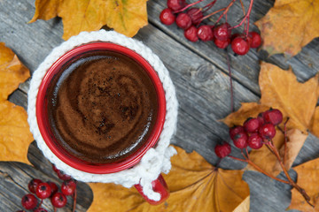 Hot steaming cup of coffee. Wool cloth mug. Autumn fall leaves.