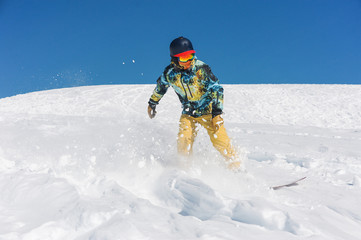 Fototapeta na wymiar Professional snowboarder in bright sportswear riding down a mountain slope
