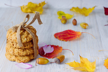 A stack of cookies tied with a rope next to autumn leaves on the table. Autumn still life.