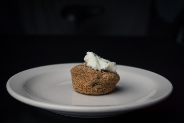 Single mini-muffin on a white plate with frosting