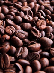 Close up portrait of dense bunch of aromatic roasted brown coffee beans in variety of brown shades
