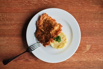 a plate with mashed potatoes and a toasted egg with tomatoes and a fork. The view from the top