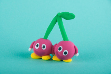 Funny fruits. Two red cherries with eyes, hands, foots and green stems, leaf staying on blue background