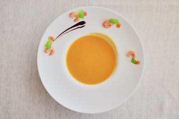 Vegetable cream soup with carrot in white bowl. Top view on a rough white cloth. molecular kitchen
