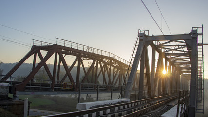 A railway bridge in the morning fog or smoke through which the rays of the sun shine