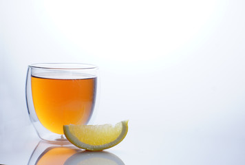 Tea in a transparent glass on a white background next to a slice of lemon and place for text on the right