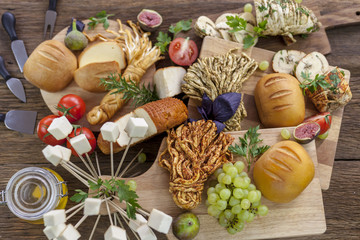 Smoked cheese pigtail, Traditional Polish smoked cheese, Chechil cheese on the Wood background. Smoked cheese    on a cutting board, whith grape, basil, figs, a large assortment of cheeses, closeup