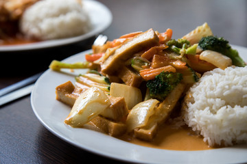 Vegetarisch rotes Thai Tofu Gemüse Curry aus Wok mit Reis im Restaurant