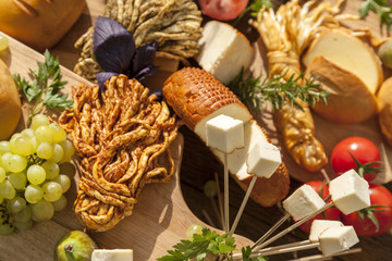 Smoked cheese pigtail, Traditional Polish smoked cheese, Chechil cheese on the Wood background. Smoked cheese    on a cutting board, whith grape, basil, figs, a large assortment of cheeses, closeup
