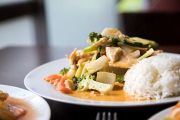 Rotes Thai Curry aus Wok mit Huhn, Gemüse und Reis im Restaurant