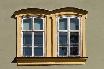 Vintage looking double window in European style, green facade with yellow border