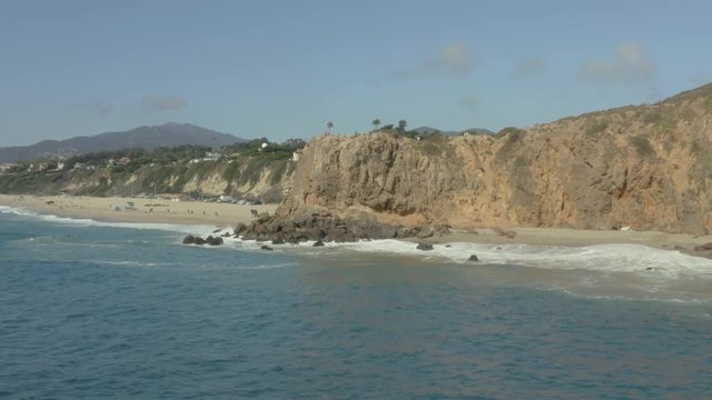 Aerial fly around of a cliff on the beach.
