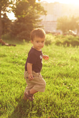 Sunny portrait of happy toddler  in casual clothes, running in the park, green grass