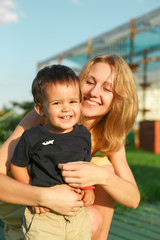 warm portrait of young happy woman hugging smiling male toddler, little child, positive emotions